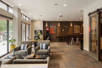 A modern waiting room with grey couches and a wooden floor at Regatta Sloans Lake Apartments, Denver